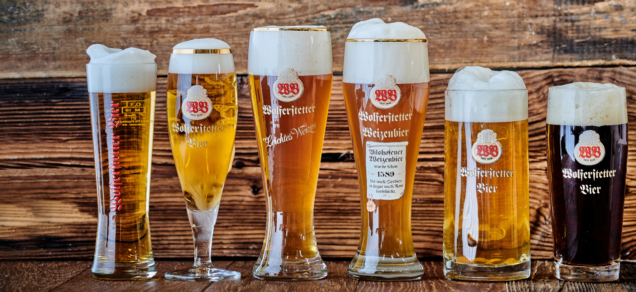 Sechs verschiedene Biere der Wolferstätter-Brauerei Vilshofen in passenden Gläsern